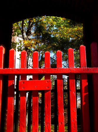A red picket fence frames a lush courtyard behindの写真素材