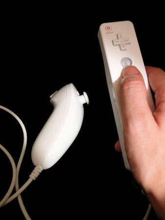 Hand holding video game control over black backgroundの写真素材