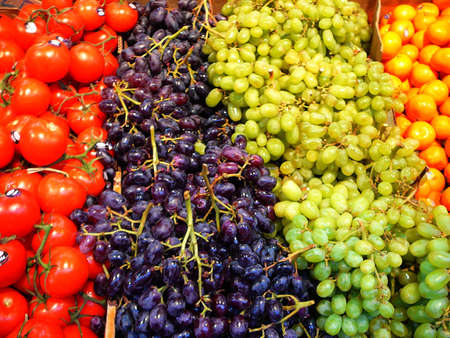 Fresh Produce at Market: Tomatoes, Red and Green Grapes, and Tangerinesの写真素材