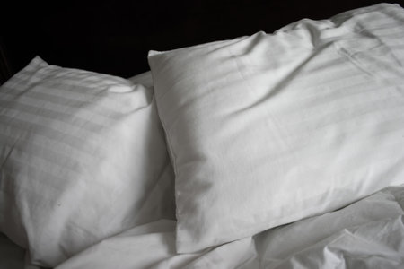 Twin white pillows resting against black headboard in bedの写真素材
