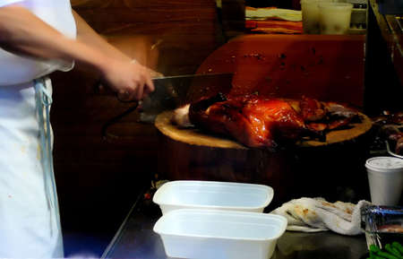 Closeup of Chef in Chinese Restaurant Slicing Roasted Duck with Meat Cleaverの写真素材