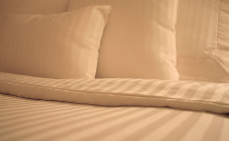 Detail of bed with set of crisp striped sheets and pillows