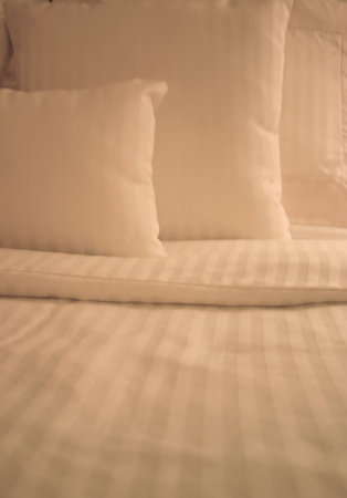 Detail of bed with set of crisp striped sheets and pillows