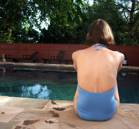 Woman relaxing next to backyard swimming pool