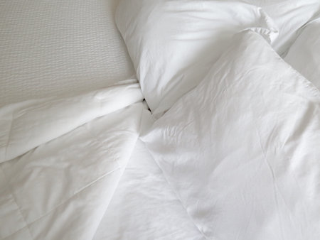 Detail of bed with set of crisp white sheets and pillowsの写真素材