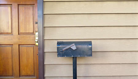 Black metal mailbox outside front door of homeの写真素材