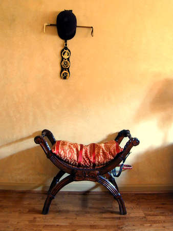 Wooden bench with cushion by wall in sunlightの写真素材
