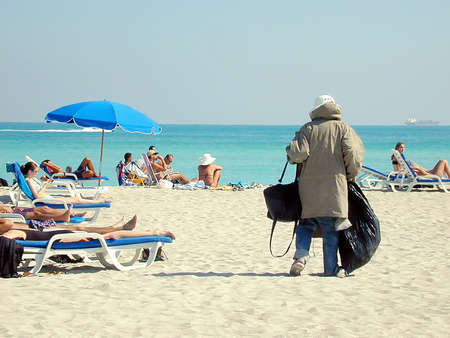 Homeless man with winter coat on beach in summerのeditorial素材