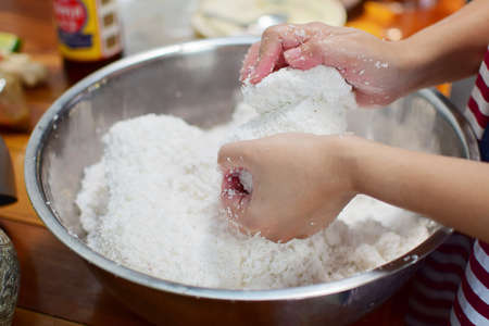 hands press cream out of the coconut meat into the bowlの写真素材