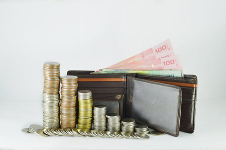 Coins stacking level with cash in the purse put on the white background.