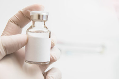 Hand in medical glove holding vaccine vial, close-up view, covid-19 concept.