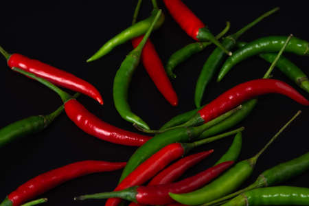 Red and green chili peppers on black background.の写真素材