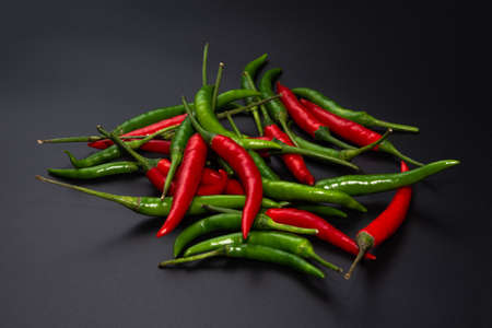 Red and green peppers on black marble cutting board.の写真素材