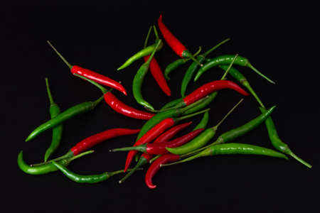 Red and green chili peppers on black background.の写真素材