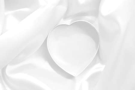Heart shaped stainless steel on white satin background, Valentine day background, White background, Wallpaper and background.の写真素材
