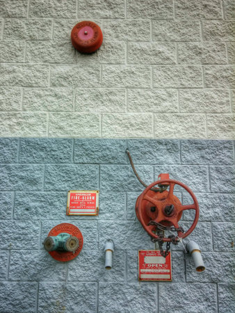 Circular red fire suppression equipment against blue and gray square block wall.