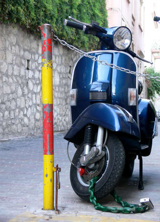 A blue italian scooter parked nad securely loccked on a alley in the city of Taormina Sicily Italyの写真素材