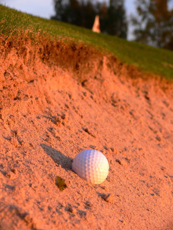 A golf ball in the green bunker close to the flagの写真素材