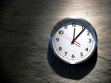 An analog clock hanging on a solid stone wall
