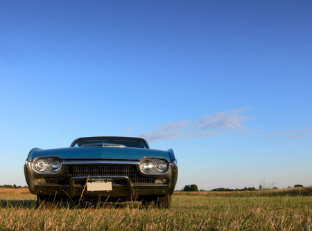 A classic american car parked in a field under a bright blue skyのeditorial素材