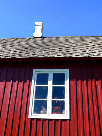 A white painted window on a small red wooden houseの写真素材