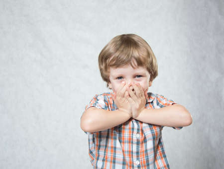 the boy pushes both hands to his faceの写真素材