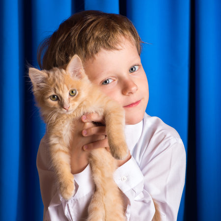 A boy with ginger kitten on hand pressed against the cheekの写真素材