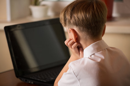 boy with laptop at the table rested his head on the arm angle back