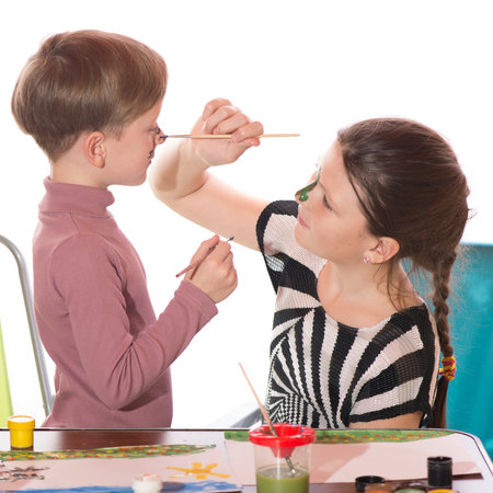 a boy and a girl having fun painting face paintingの写真素材