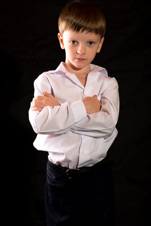 Portrait of a boy on a black background with the white shirt. Blue eyes blond. Different camera angles while standing.の写真素材