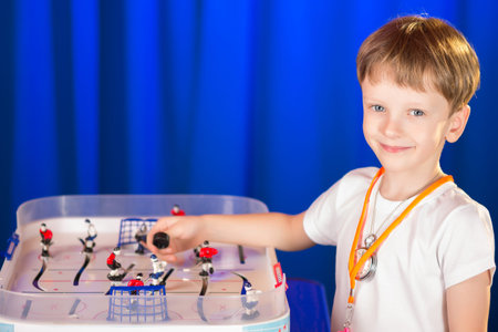 Boy playing table hockey. A child holds a hockey game at the table. Schoolboy hockey referee .