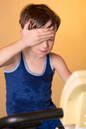 The child is trained on a stationary bike . Leads a healthy lifestyle. The boy develops muscles . Tired and sweaty . Sport generation.の写真素材