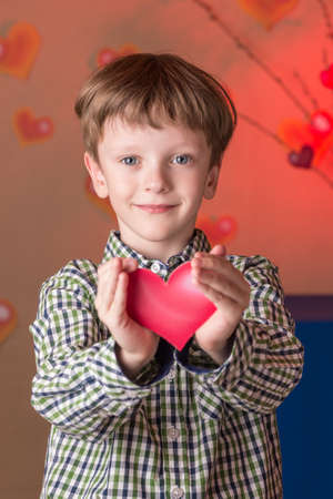 The child makes a gift on Valentines Day scarlet heart.の写真素材