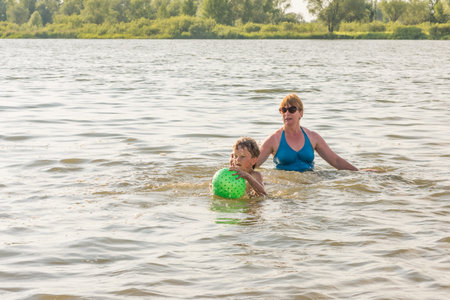 Family fun with a ball on the river in summerの写真素材