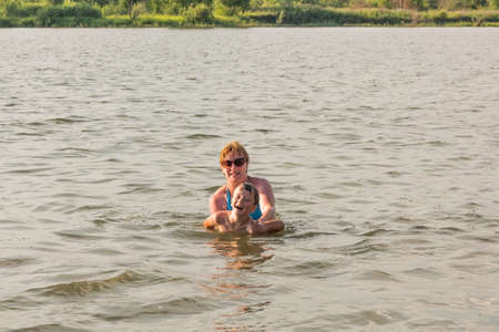 Family fun with a ball on the river in summerの写真素材