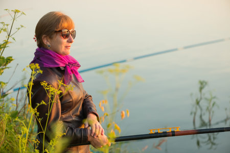 woman fishes on the river in the morning at dawnの写真素材