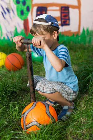 Boy soccer ball pump pumps on the playgroundの写真素材