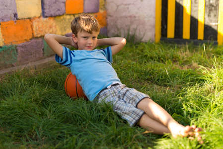 Boy with basketball sitting on green grassの写真素材