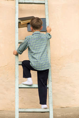 Boy sitting stairs. Read book. Human reading book ladder. Window and wall ladder.の写真素材