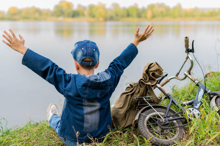 A child on a bicycle with a backpack on the river looking for water