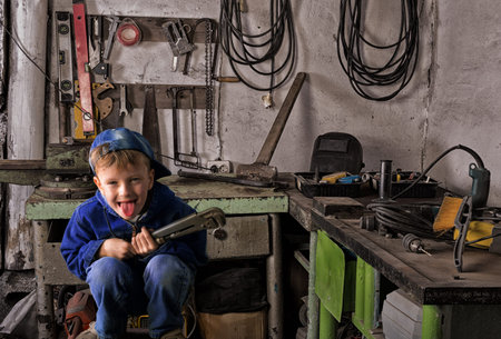 The boy of school age in the metal workshop with instrument in handの写真素材