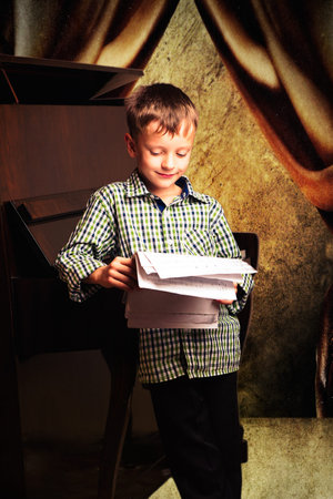 Boy with notes in their hands standing around the piano ready for action in front of the audienceの写真素材