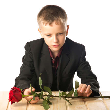 The guy with the red rose. The boy is sitting at the table and sad. The young man laid the flower in front of him.の写真素材