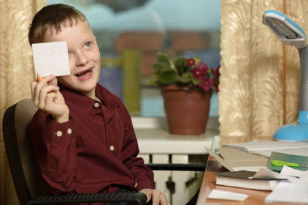 The guy at the office uses computer technology.Demonstrates a paper note.Sits in a chair in a burgundy shirt.の写真素材