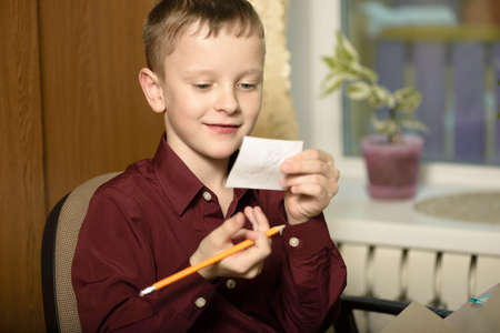 The guy at the office uses computer technology.Demonstrates a paper note.Sits in a chair in a burgundy shirt.の写真素材