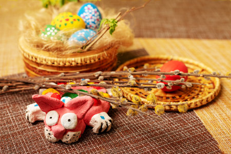 Easter still life. A nest of straw and flax with painted eggs and a rabbit. Wicker basket stands on...