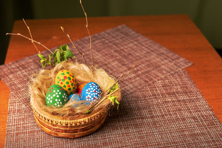 Easter still life. A nest of straw and flax with painted eggs. Wicker basket stands on decorative...