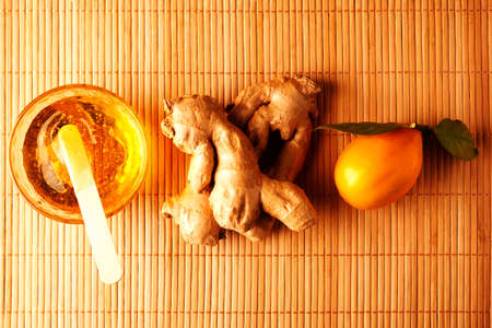 On a napkin from a bamboo there are cups with a turmeric, honey, ginger. Useful spicery. Fragrant spices. Natural vitamins. Citrus. Top view.の写真素材