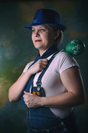 A woman holds a lifeless balloon hanging on a string. Blue hat and jumpsuit and tie. Emotion expresses hope, pity, and a desire to help. Perhaps it will fly up someday. Do not be discouraged.の写真素材
