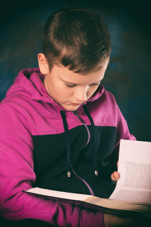 The boy holds a book in his hands and reads with interest. Diligent student. The future of the...